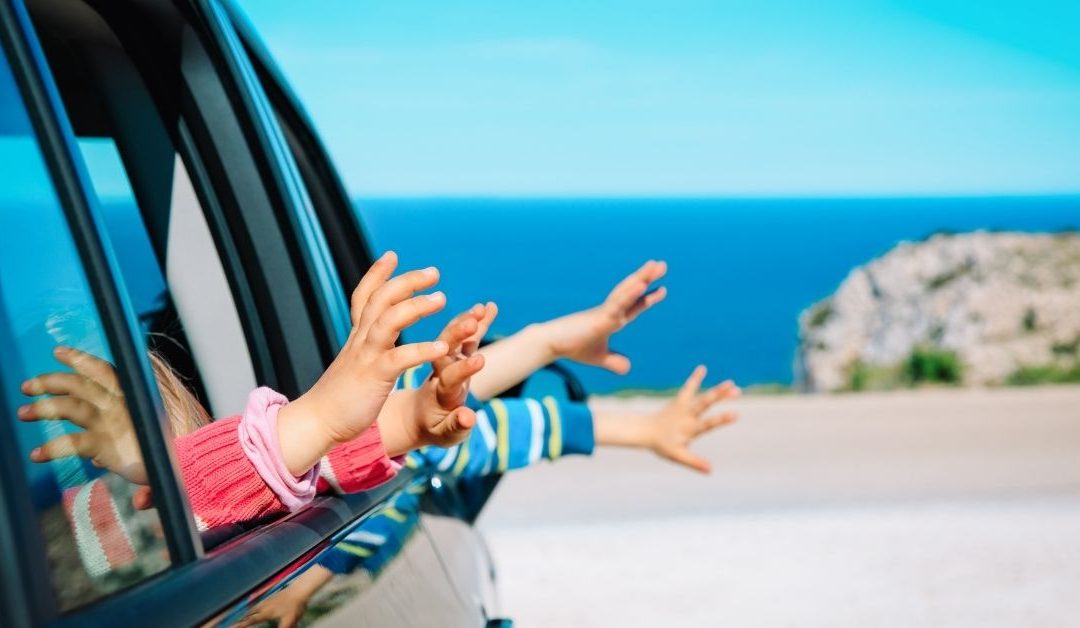 Image of kids feeling the air out the window as parents drive them somewhere.