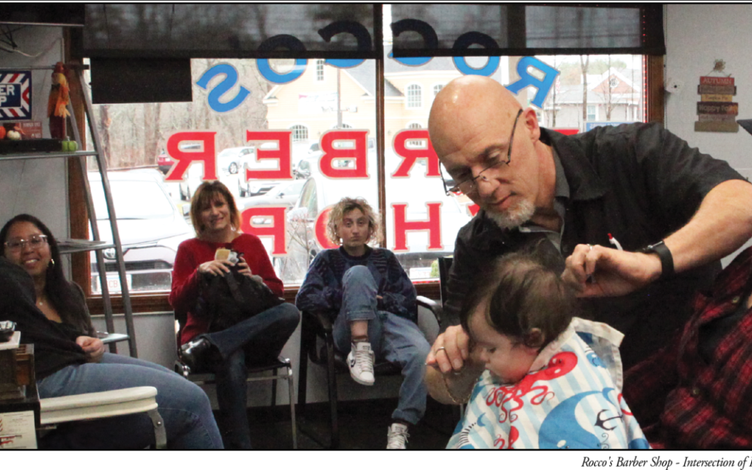 Hair Heir: Barbershop Owner Rocco DiTullio II Cuts the Hair of his Grandson, Rocco IV Who’s Sitting on His Dad,  Rocco III, as Family Members Look On